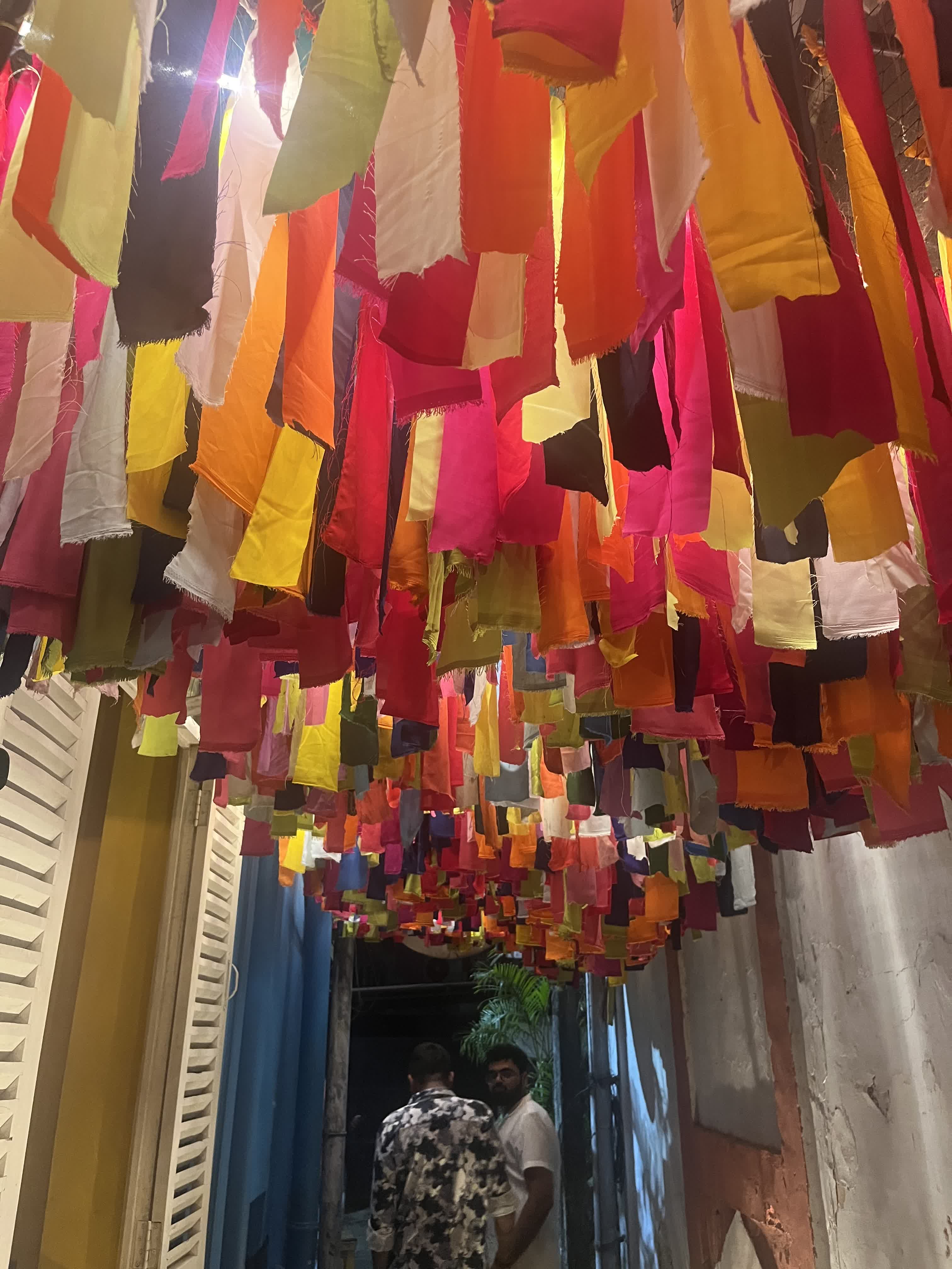 A lane strung with bright hanging fabric streamers at night