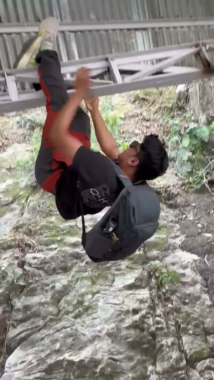 Hanging off a metal railing on the trail, goofing around