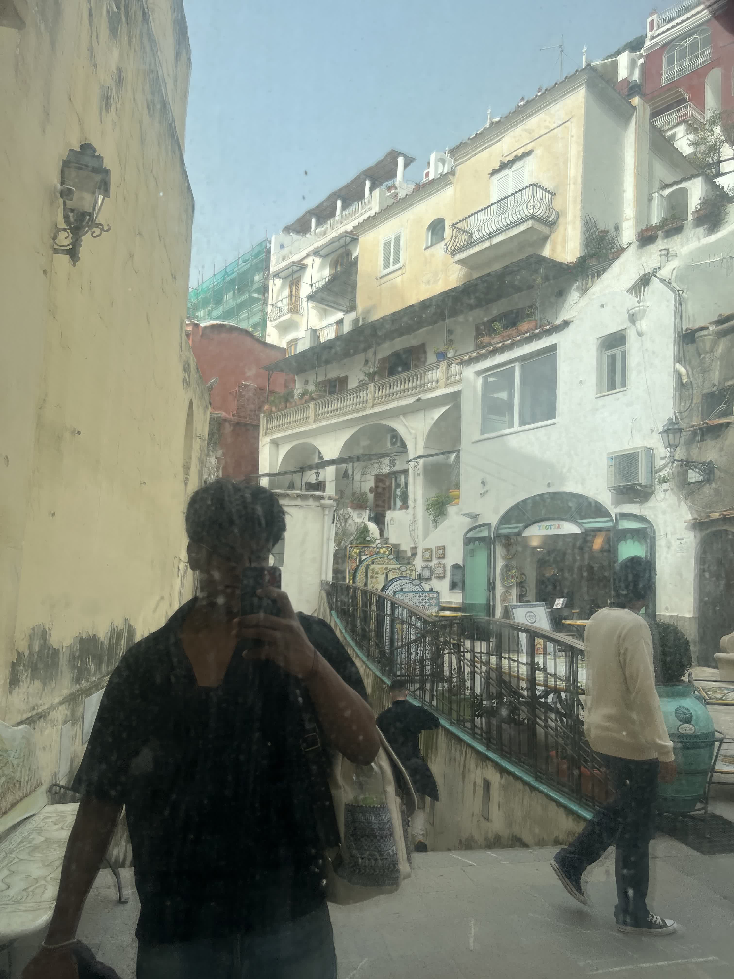 Reflection in a shop window framing the pastel cliffside houses of Positano