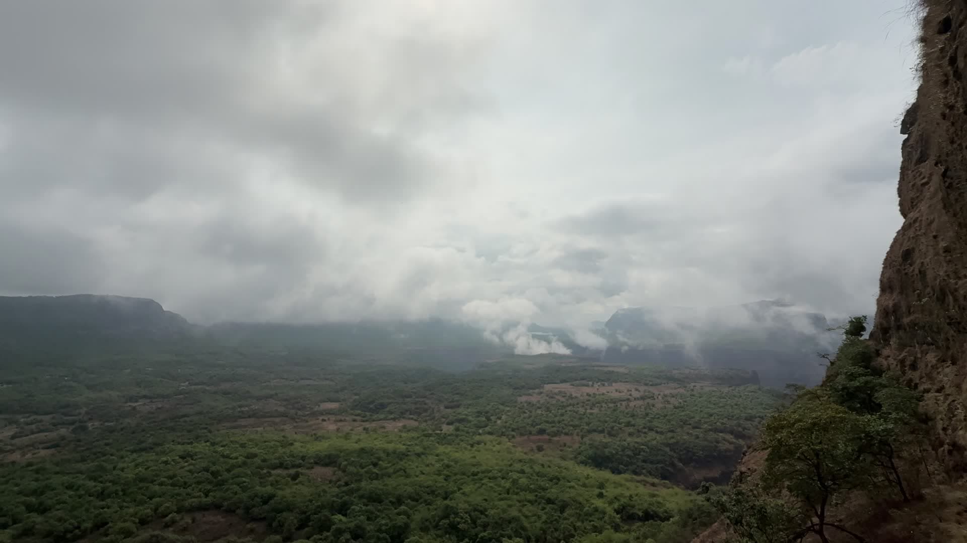 Monsoon clouds rolling over the green Sahyadri valley from the cliff edge