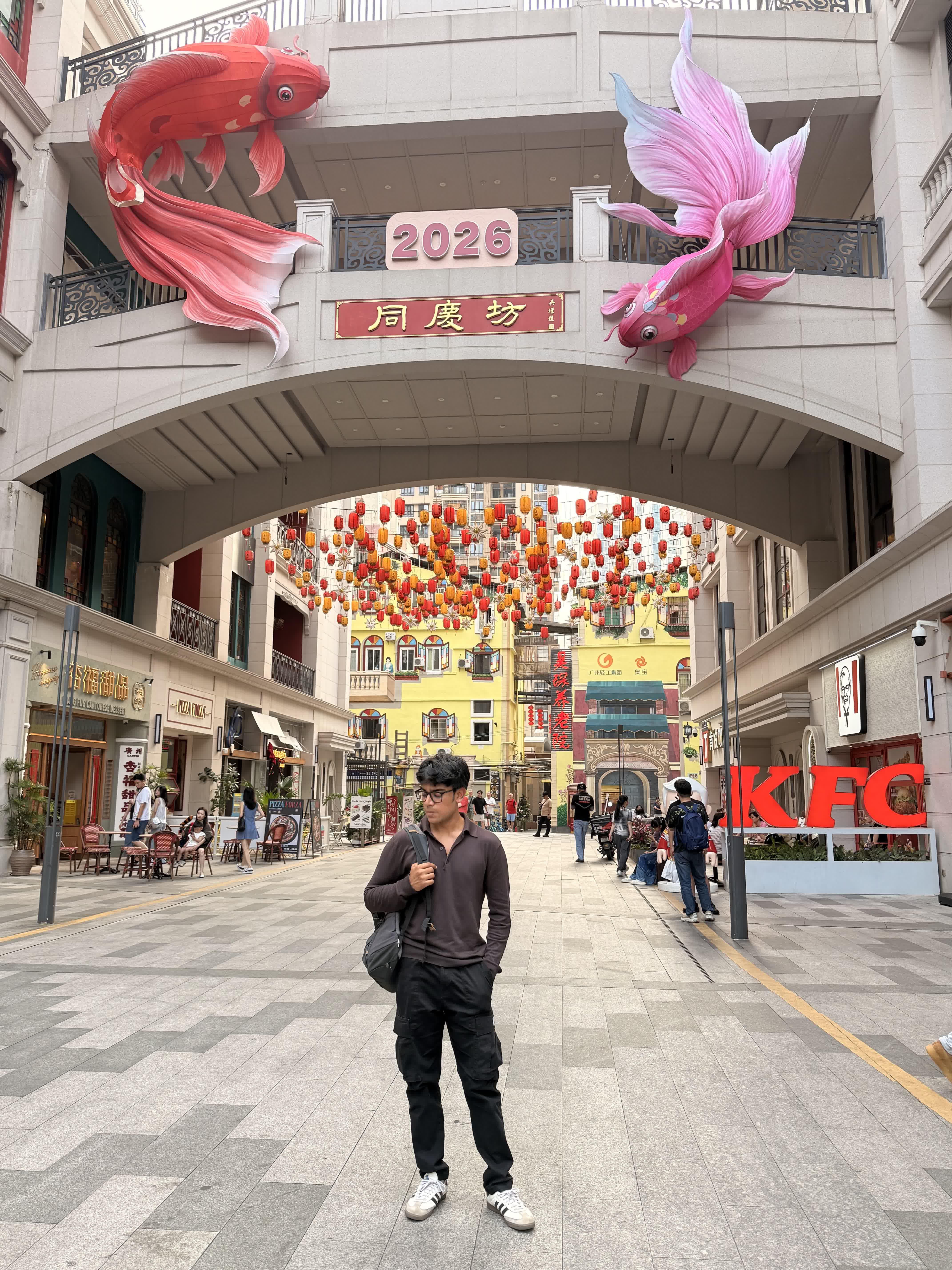 Standing under giant koi sculptures and red lanterns at the Tongqingfang arch