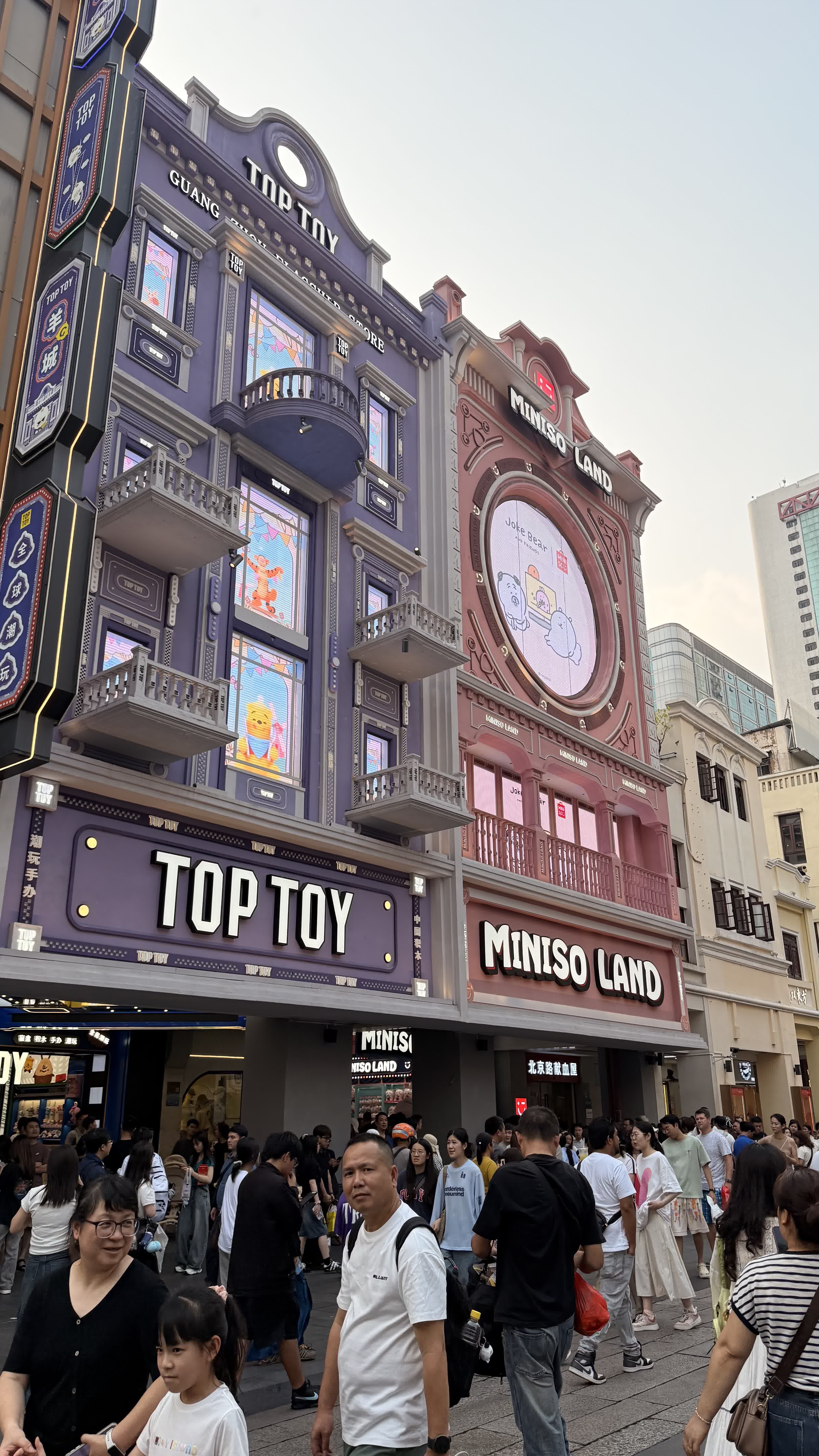 Ornate TOP TOY and MINISO storefronts on a busy pedestrian street