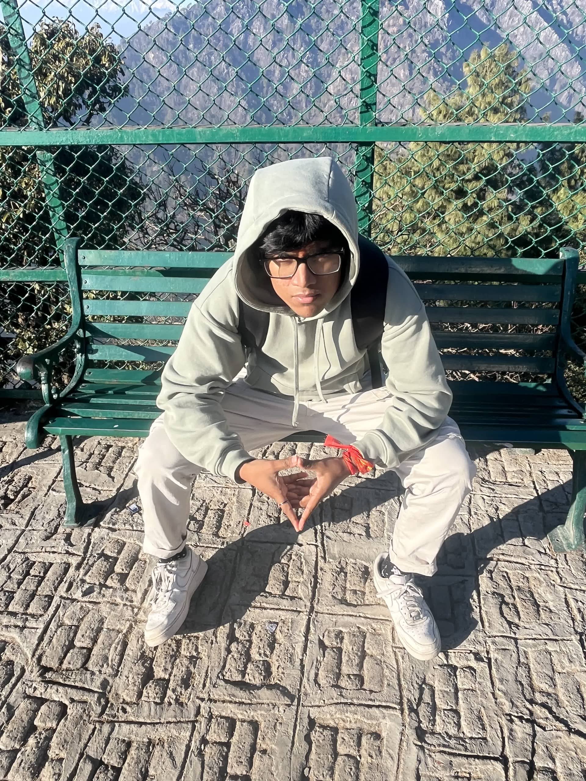 Sitting on a viewpoint bench in a hoodie with a tika on the forehead