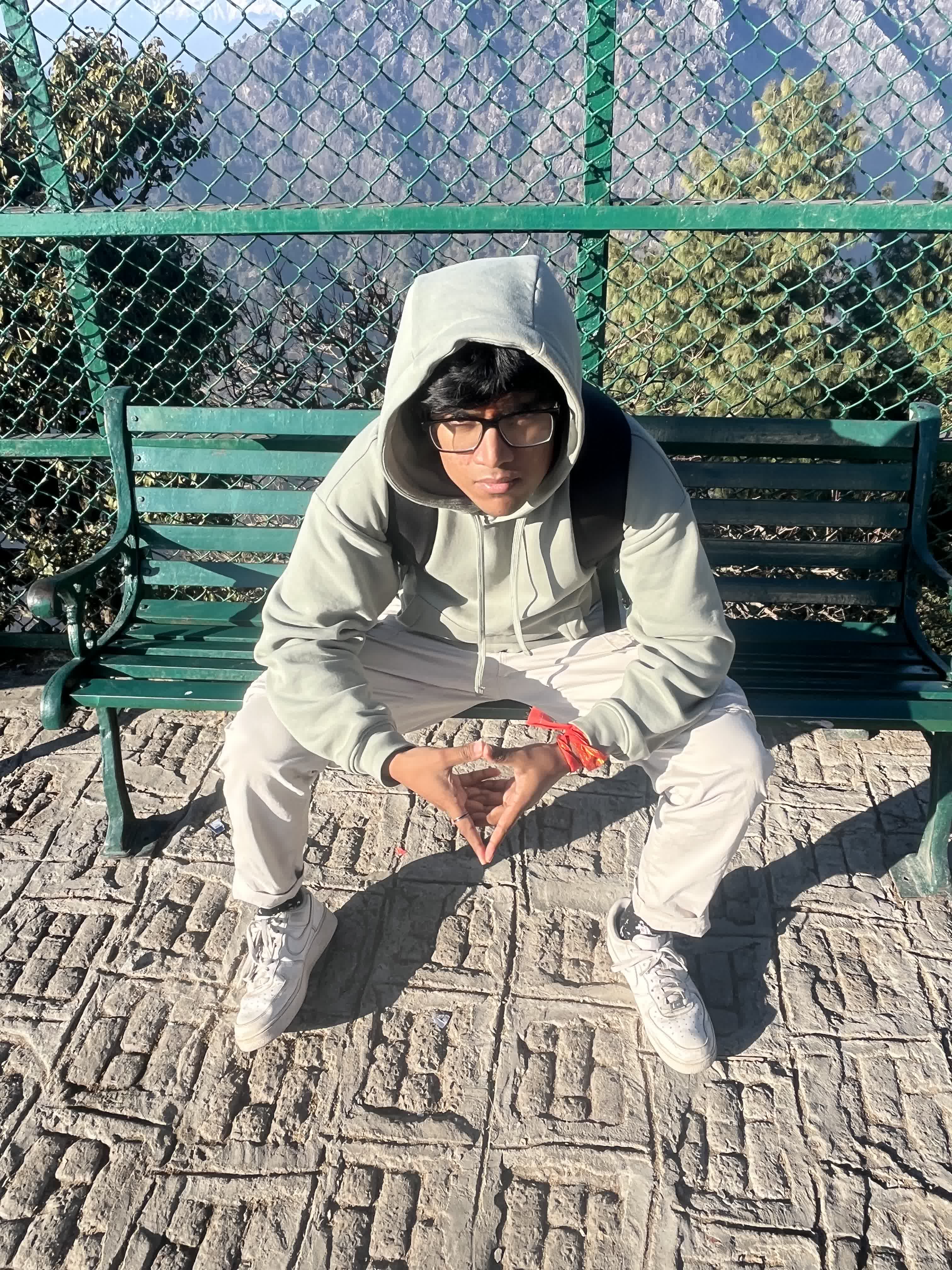 Sitting on a viewpoint bench in a hoodie with a tika on the forehead